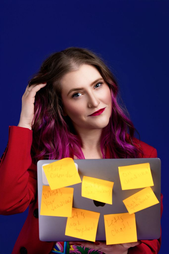 Jessica Petruk sitting with her computer that's colourfully covered in sticky notes.
